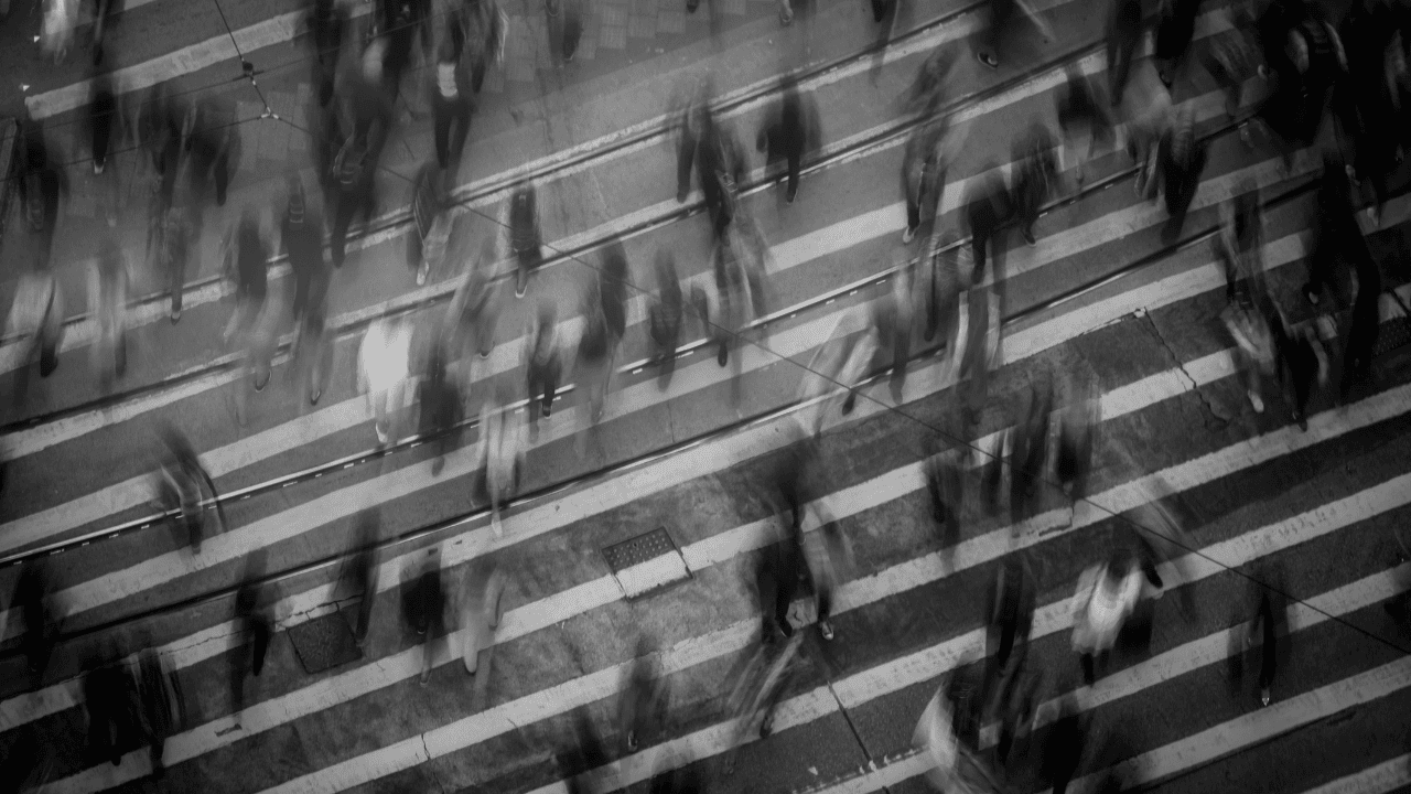 Blurred image of pedestrians crossing at a zebra crossing in black and white.